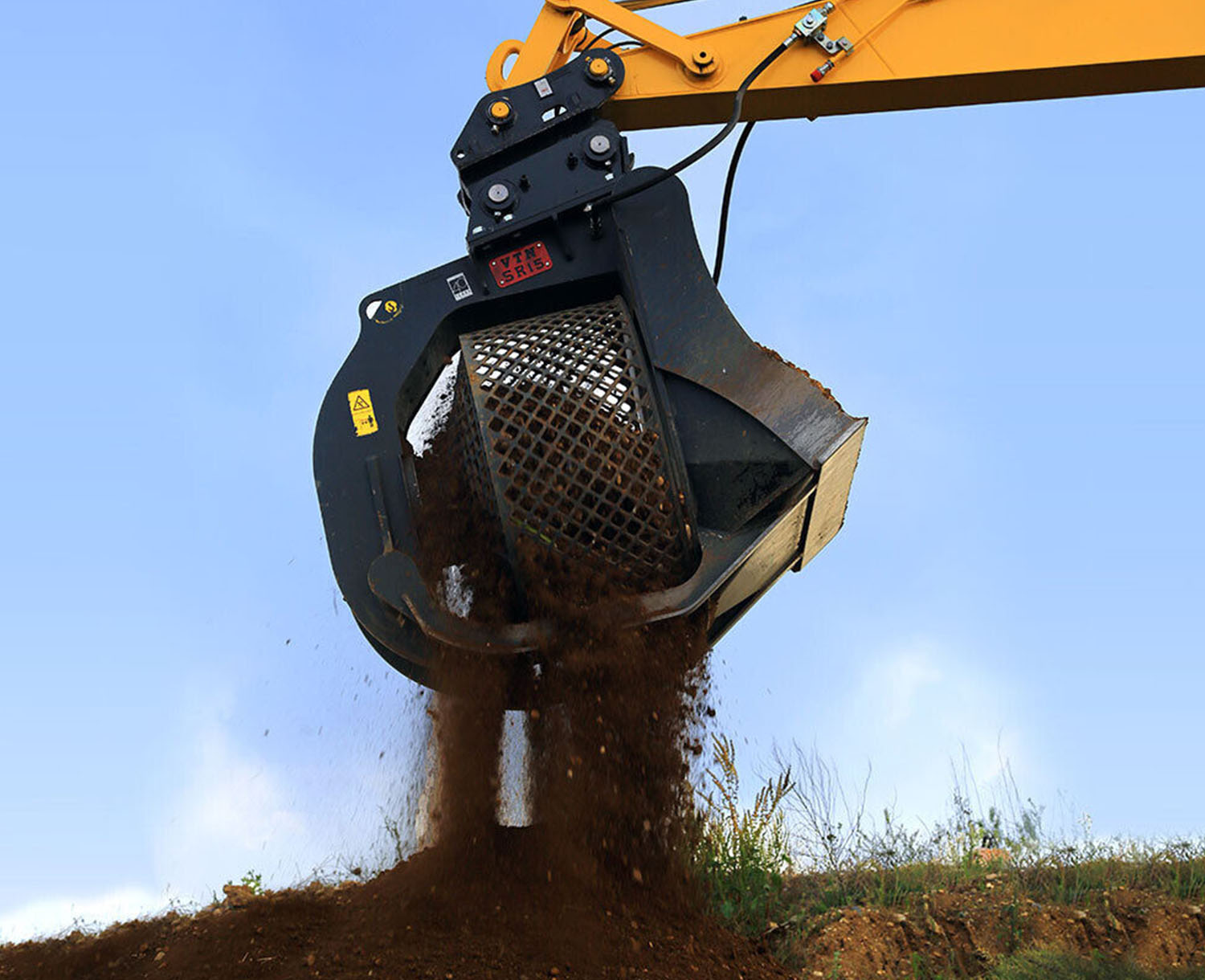right side view of the VTN skid steer screening bucket attachment on the end of a boom screening dirt